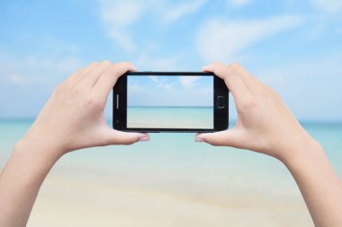 Smartphone deniz arka planda tutan el