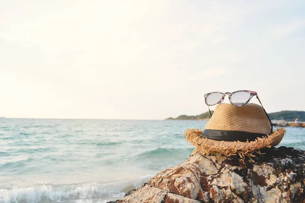 Hut und Sonnenbrille auf Felsen und Meer Hintergrund — Stockfoto