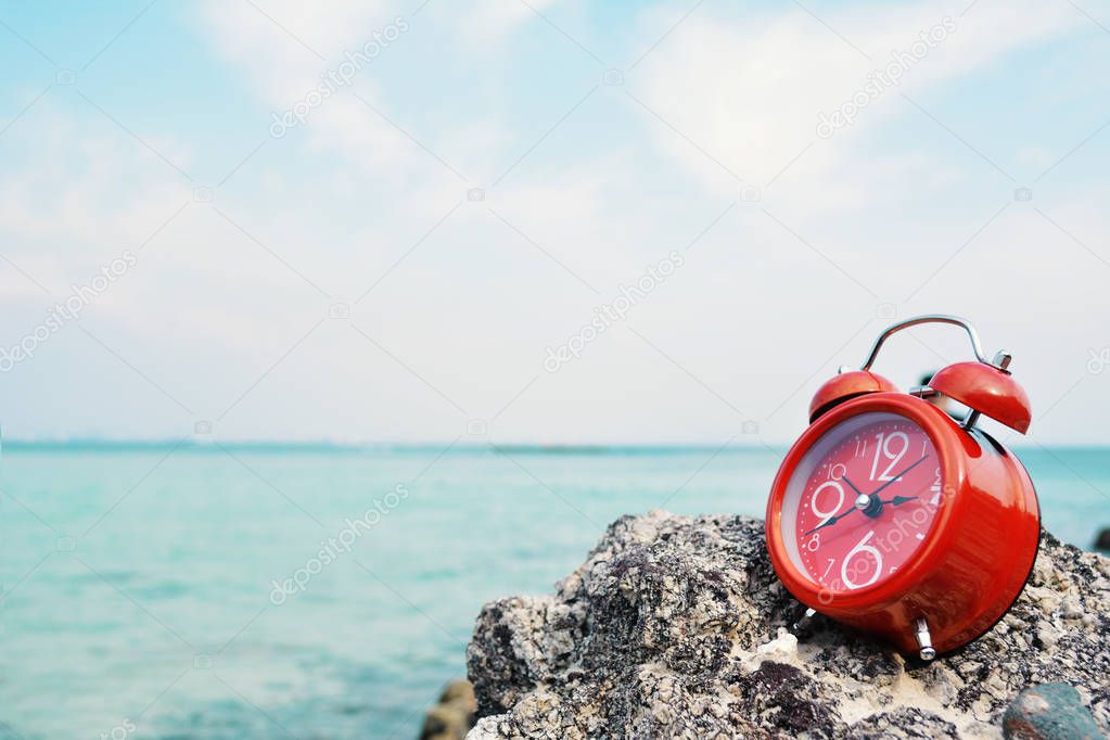 Red alarm clock on rock and sea background concept time to travel