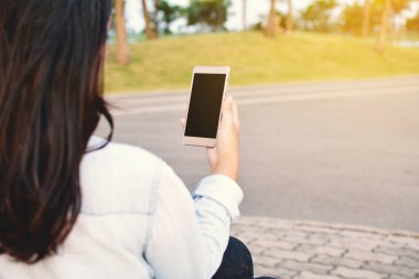 Güzel kadınlar Smartphone rahatlatıcı parkta kullanarak