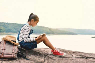 Doğa arka planda bir kitap okuma mutlu Asyalı kız
