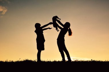 Siluet anne ve çocuk küçük köpekle oynamayı 