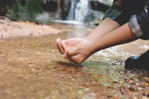 Mochila de las mujeres y agua potable en el arroyo del río —  Fotos de Stock