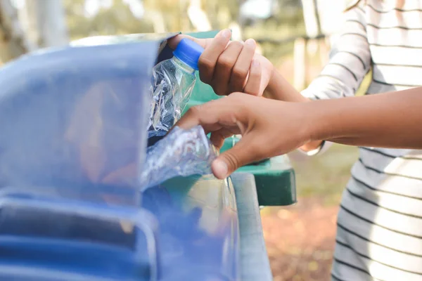 Nahaufnahme Kinder Hand hält leere Flasche in den Müll — Stockfoto