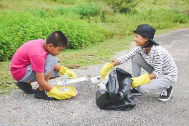 Çocuklar ellerinde sarı eldiven boş şişe plastik malzeme çekme
