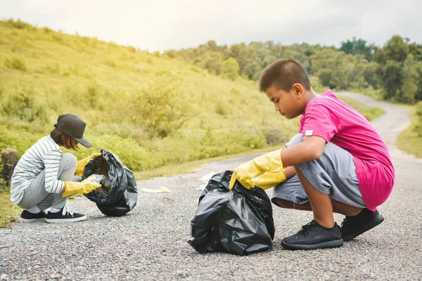 Ręce dzieci w rękawice żółty, zbierając puste butelki plastikowe do worka bin — Zdjęcie stockowe