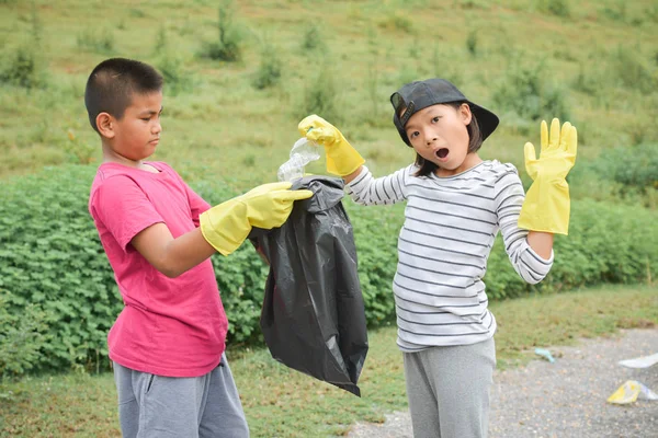 Ręce dzieci w rękawice żółty, zbierając puste butelki plastikowe do worka bin — Zdjęcie stockowe