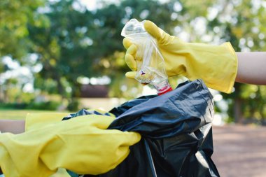 Elinde boş şişe plastik depo gözü torba içine alarak sarı eldivenler