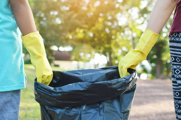 Manos en guantes amarillos sosteniendo bolsa de basura — Foto de Stock