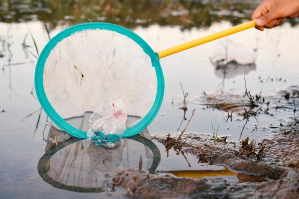 Junge nimmt leere Plastikflaschen mit der Hand auf — Stockfoto