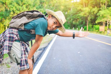 Yol ve orman arka planda mutlu Asyalı çocuk sırt çantası