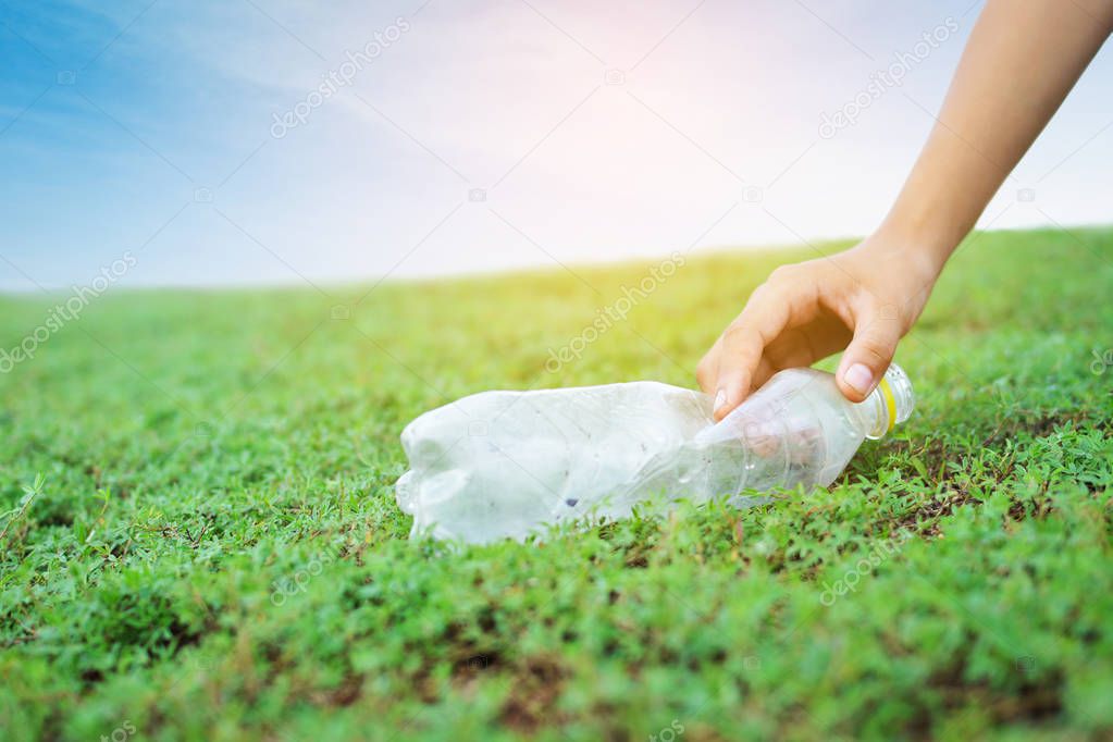 Hand picking plastic garbage on green grass