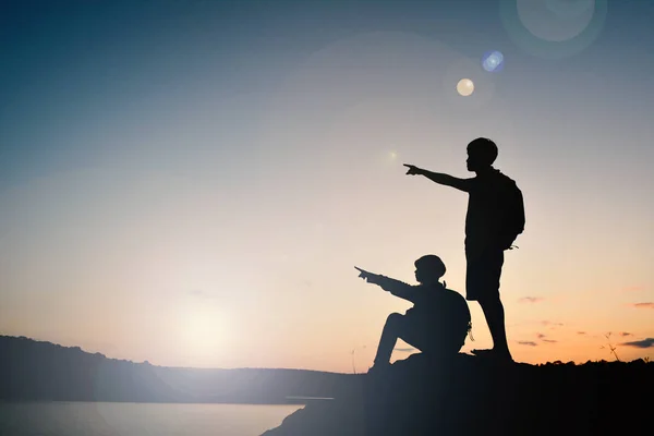 Silhouette man and girl backpacker on the top mountain — Stock Photo, Image