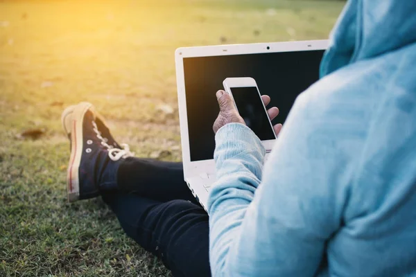 Mutlu hippi eski kadın parkta bilgisayar ve smartphone kullanarak zaman tatil, renk vintage tarzı seçici ve yumuşak odak dinlenmek