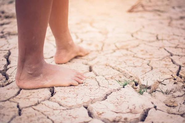 Feet of boy on cracked dry ground .concept hope and drought