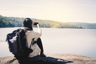 Mutlu Asyalı kadın backpacker doğa kış sezonu, Relax zaman görünümü tatil kavramı seyahat, seçici ve yumuşak odak, hippi tarzı tonunu çekim smartphone kullanarak