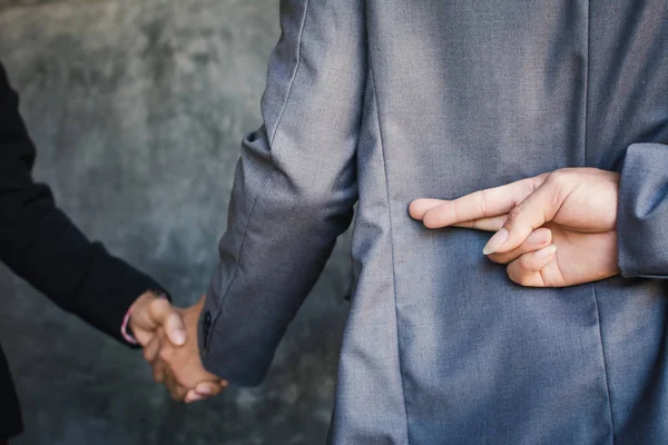 İşadamı elini sıkmak ve ihanet, odak ve mavi arka plan seçici