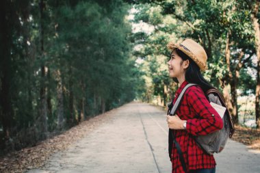 Kadın backpacker yol ve orman arka plan, Relax zamanında tatil kavramı seyahat, vintage sesi ve yumuşak odak rengini