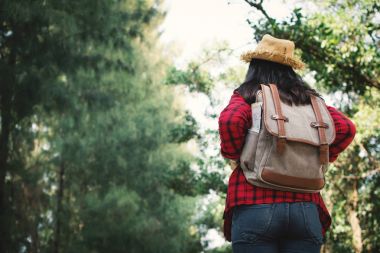Kadın backpacker yol ve orman arka plan, Relax zamanında tatil kavramı seyahat, vintage sesi ve yumuşak odak rengini