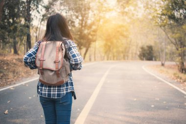 Mutlu Asyalı kadın sırt çantası içinde yol ve orman arka plan, Relax zamanında tatil kavramı seyahat, vintage sesi ve yumuşak odak rengini
