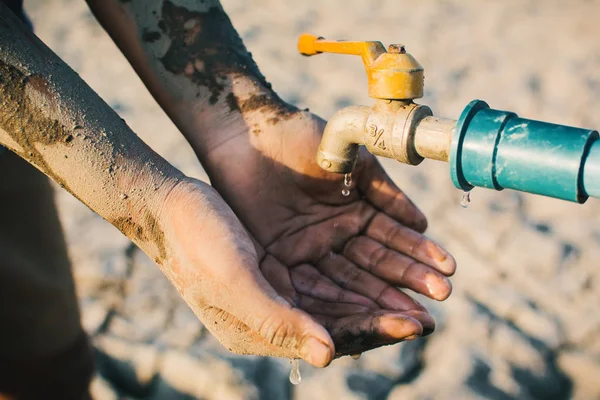 少年の手が地面の亀裂 概念の干ばつ 水危機の不足いくつかの水を飲みたいです — ストック写真