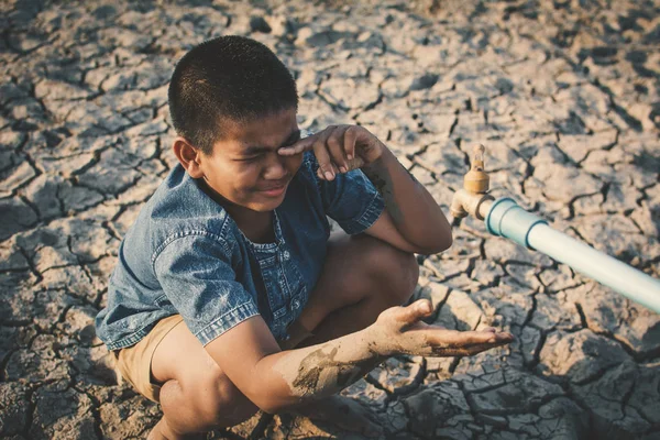 悲しい少年が地面の亀裂 概念の干ばつ 水危機の不足いくつかの水を飲みたいです — ストック写真