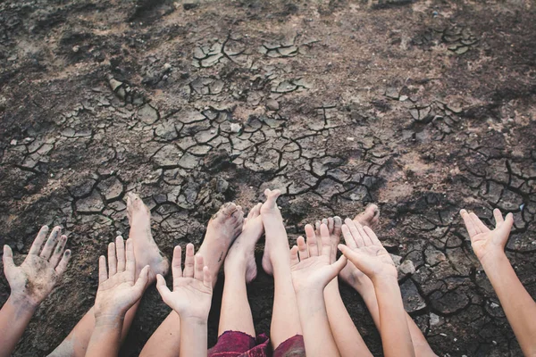 Feet and hand of children praying for the rain on cracked dry ground .concept hope and drought