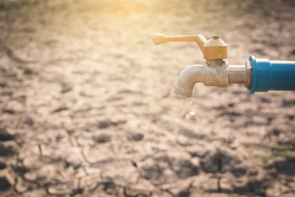 Faucet on cracked dry ground , concept drought and shortage of water