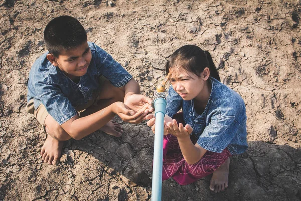 Traurige Kinder wollen Wasser auf Crackboden trinken — Stockfoto