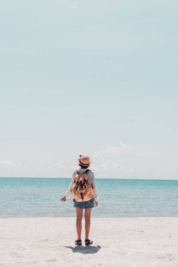 Tatlı kız sırt çantası ve kumsalda seyahat..