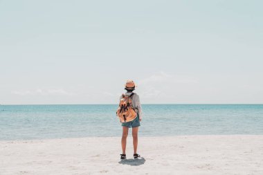 Tatlı kız sırt çantası ve kumsalda seyahat..