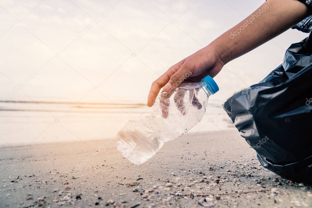 Hand picking up plastic bottle cleaning on the beach , volunteer concept.