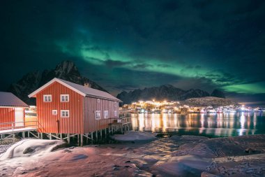 Balıkçı köyündeki kırmızı ahşap ev, Re üzerinde aurora borealis olan.