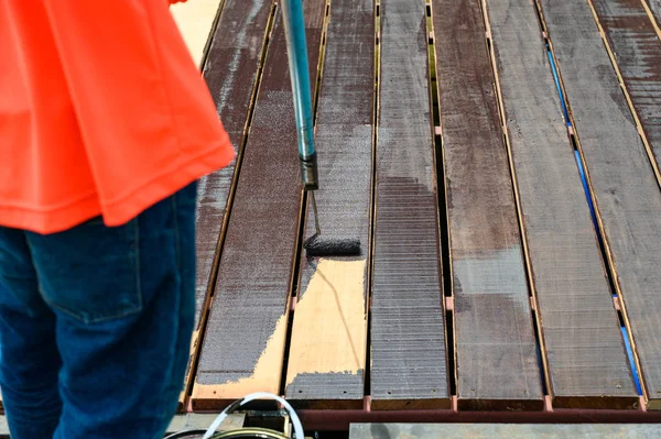 Pintura de trabajador con rodillo de pintura en suelo de madera — Foto de Stock