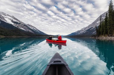 Traveler canoeing on Maligne lake with canadian rockies reflecti clipart