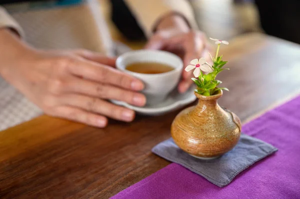 Tahta masada sıcak çay tutan kadın elleri. — Stok fotoğraf
