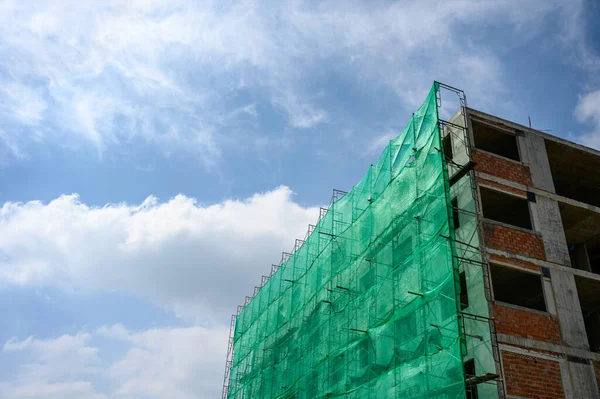 Estrutura de construção com sombra de rede e andaimes cobertos — Fotografia de Stock