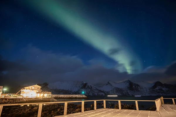 Aurora boreal o auroras boreales sobre la montaña nevada con hous —  Fotos de Stock