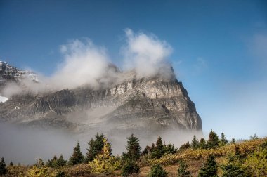 Assiniboin 'de mavi gökyüzünde sis akan büyük kayalık dağlar.
