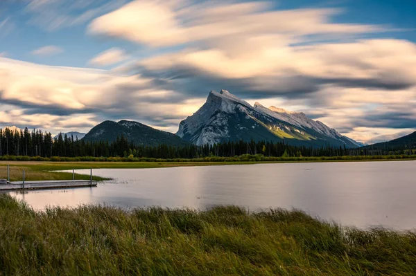 Mount Rundle i Vermillion sø med træ mole på solnedgang ved Ba - Stock-foto