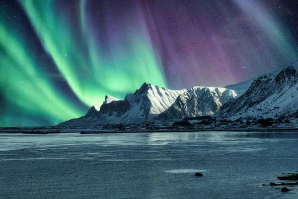Aurora Borealis, Kuzey Işıkları Lofo 'daki karlı dağın tepesinde.