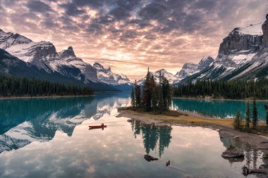 Traveler canoeing with rocky mountain reflection on Maligne lake at Spirit island in Jasper national park, Canada clipart