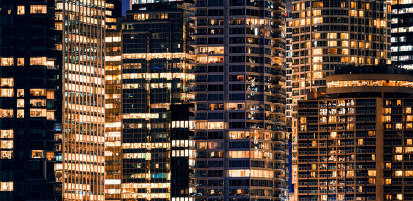 Panorama Facade windows of illuminated modern skyscraper with office building at night