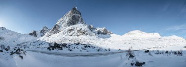 Norveç 'in Lofoten adalarındaki Nordland' da mavi gökyüzü ve karayolu ile karlı dağ manzarası