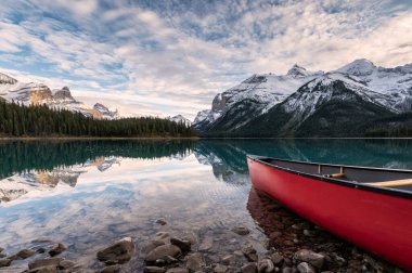 Maligne Gölü 'ne park etmiş kırmızı kano Kanada' daki Jasper Ulusal Parkı 'ndaki Spirit Adası' nda Kanada kayaları yansıtıyor.