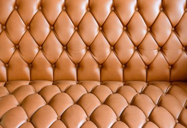 Portakal rengi deri kanepe. Arka planda desenli.