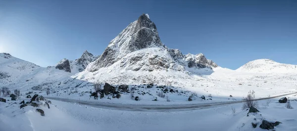 Panorama of snowy mountain range with blue sky and highway in Nordland at Lofoten islands, Norway