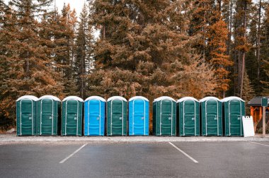 Ulusal parktaki sonbahar ormanlarında yeşil, mavi taşınabilir kimyasal tuvaletler.