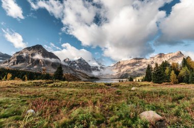 Kanada 'nın British Columbia kentindeki eyalet parkında sonbahar ormanlarında Magog Gölü ve mavi gökyüzü ile Assiniboine Dağı manzarası