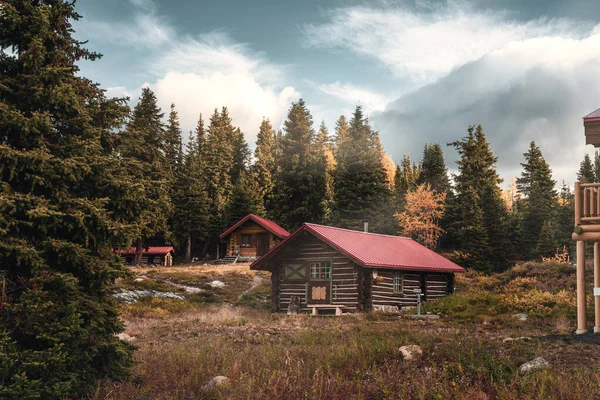 Sonbahar ormanlarında güneş ışığı alan ahşap kulübeler sabah saatlerinde Assiniboine il parkında, Kanada